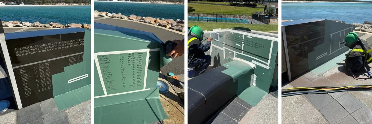 Memorial wall engraving and installation process by workers near waterfront