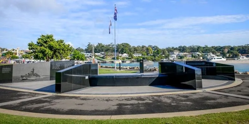 Completed war memorial installation overlooking a waterfront with surrounding parkland.