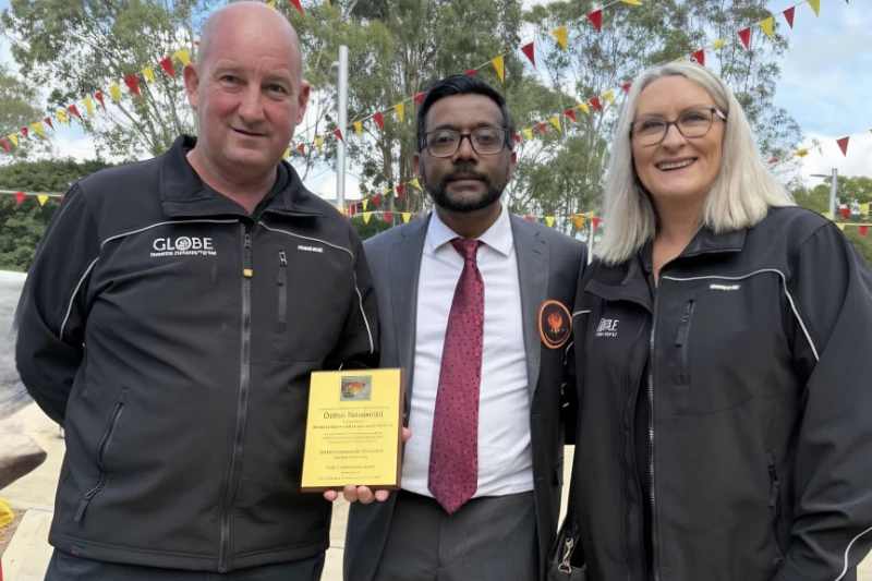 Three people holding an Outstanding Achievement award at the Tamil Community Memorial event.