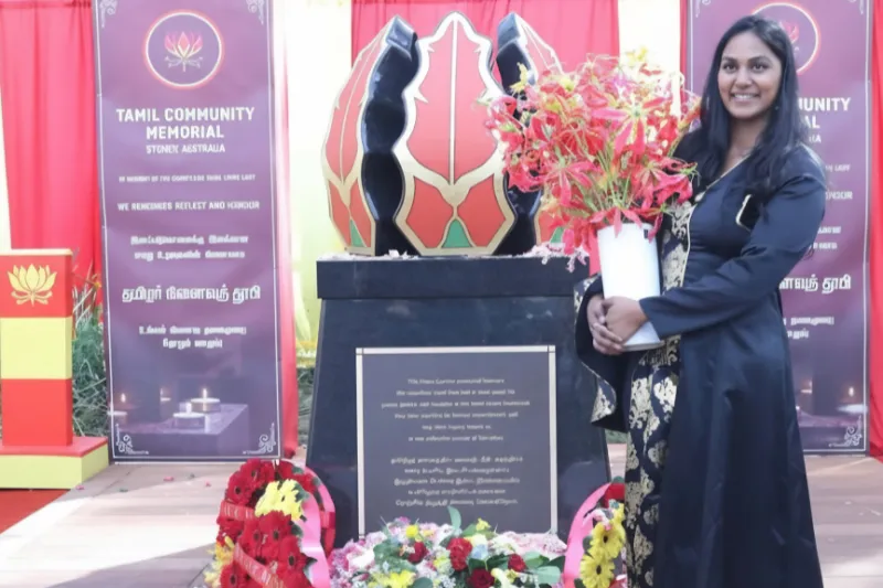 Woman holding flowers beside the Tamil Community Memorial in Sydney.