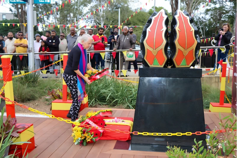 Woman laying a floral wreath at the Tamil Community Memorial during the unveiling ceremony.