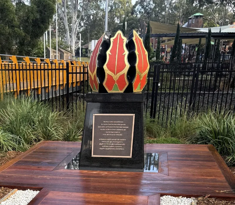 A close-up side-by-side visual comparison showing a cluster of real red and yellow flame lily flowers (Karthigai flowers) on the left, next to the final black granite monument sculpted in their likeness on the right.